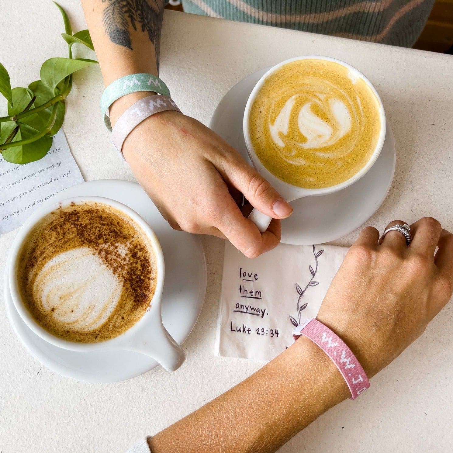 Pink WWJD x HWLF elastic bracelet on a wrist at a cafe
